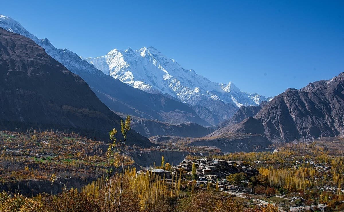Rakaposhi’s snowy face above a Hunza village and terraced fields lined with yellow autumn poplars