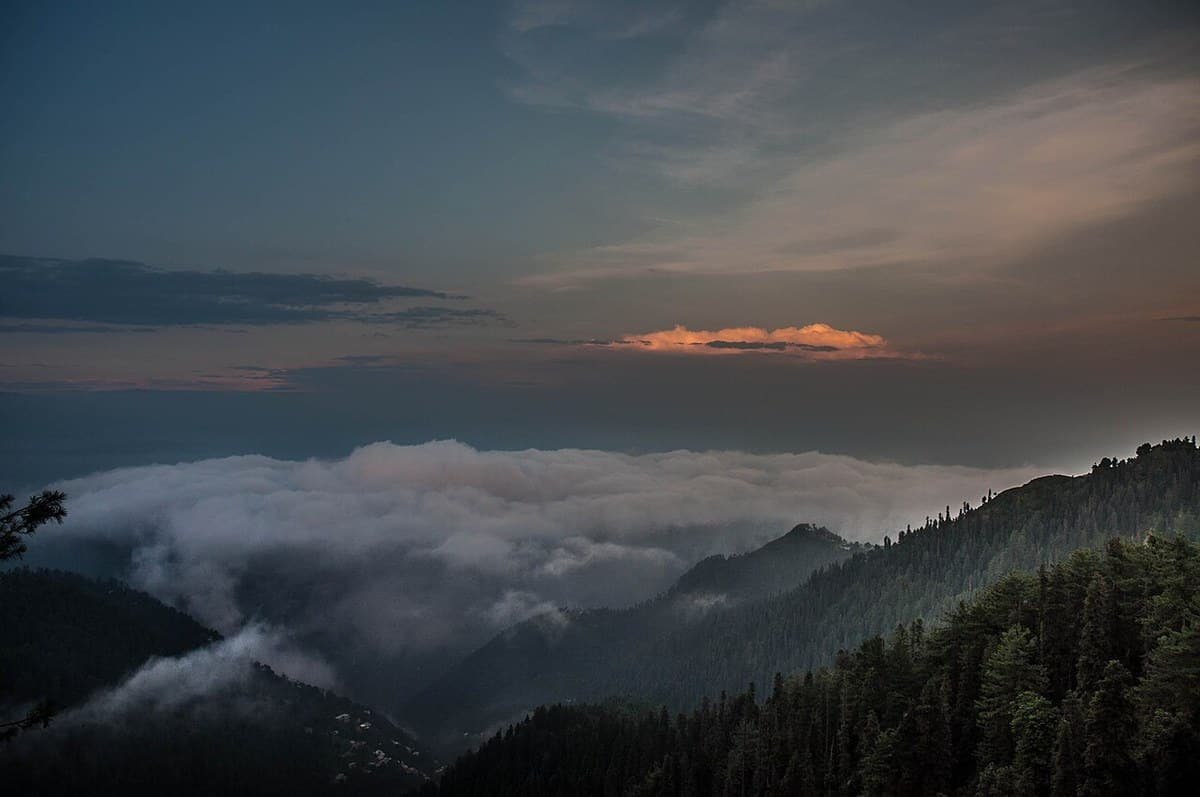 Pine-covered ridges of the Galiyat at dusk, with monsoon cloud filling the valleys below