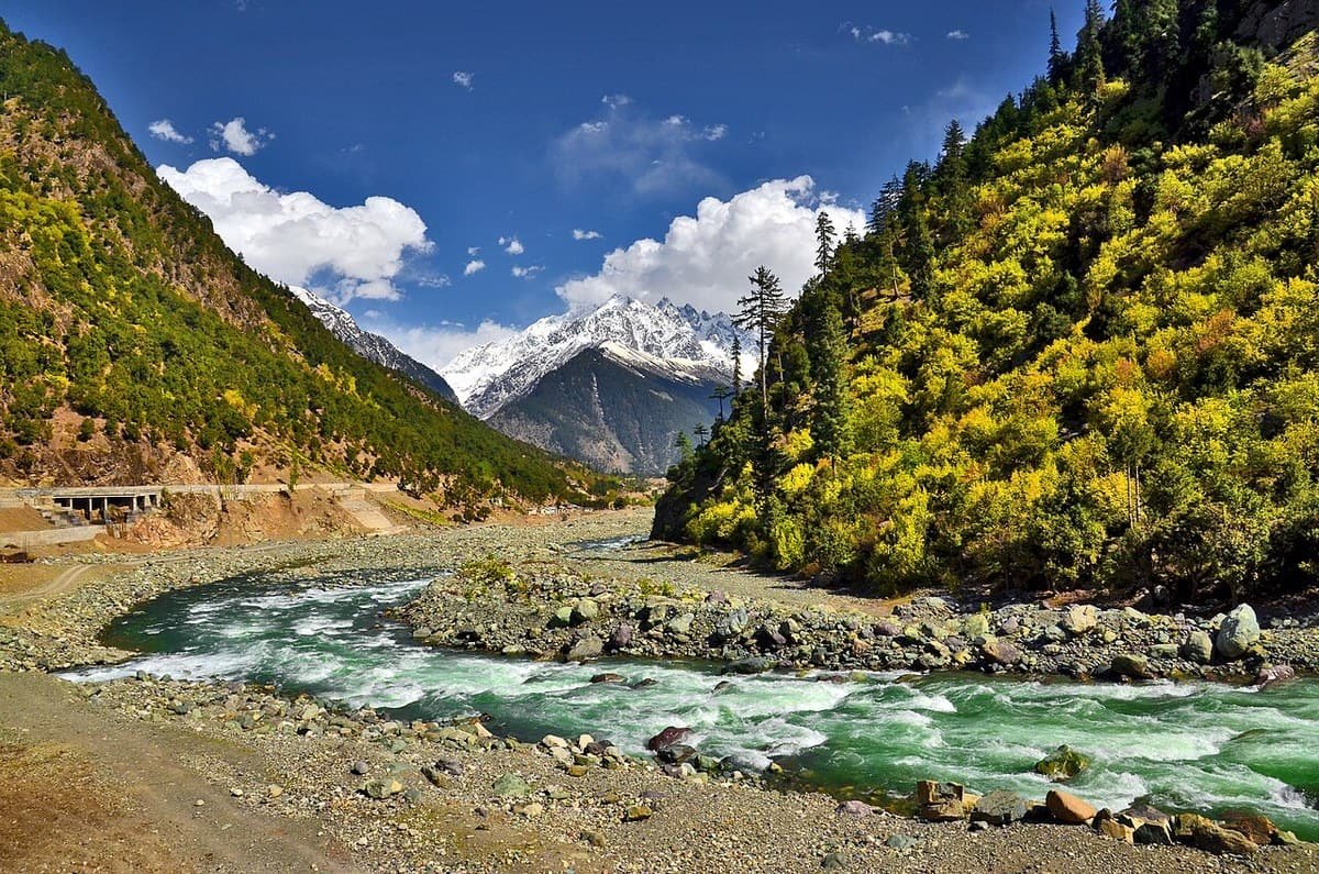 The green Swat River at Kalam, between pine-covered slopes and a snow-capped peak