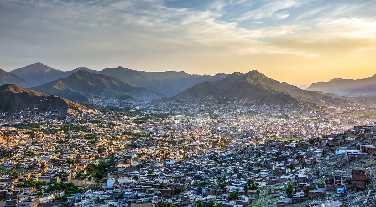 Mingora's dense houses spread across the Swat valley floor toward layered mountains at sunset.